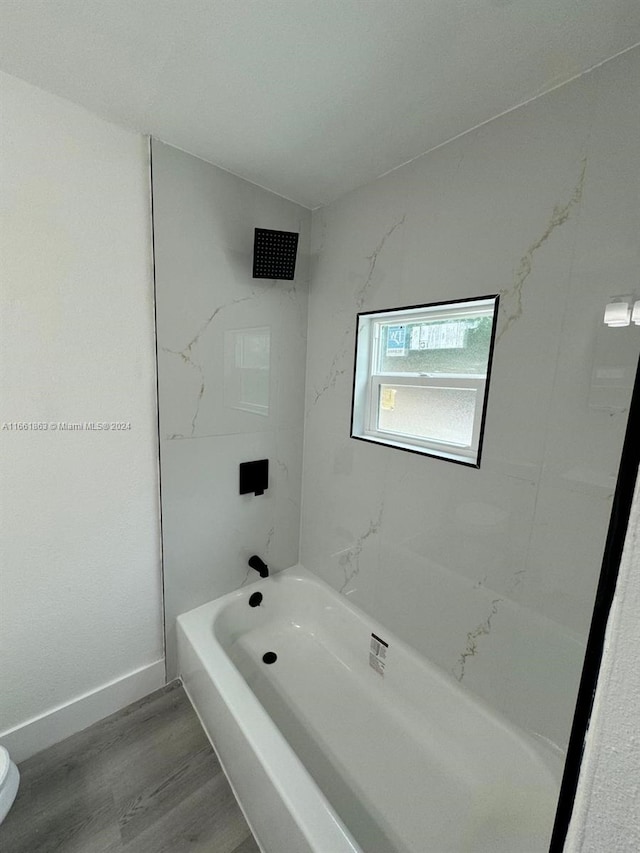 bathroom with tiled shower / bath, hardwood / wood-style floors, and toilet