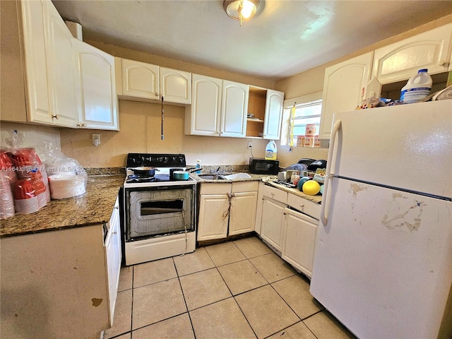 kitchen featuring dark stone counters, light tile patterned floors, and white appliances