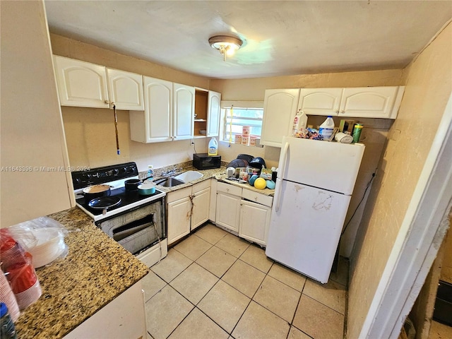 kitchen featuring dark stone counters, light tile patterned floors, white appliances, and white cabinetry