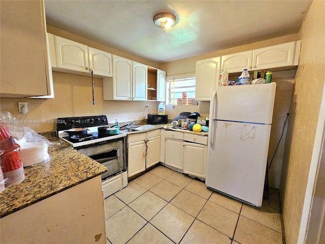 kitchen featuring dark stone counters, light tile patterned floors, white appliances, and white cabinetry