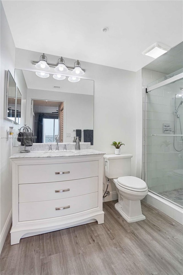 bathroom with a shower with shower door, hardwood / wood-style flooring, toilet, and vanity