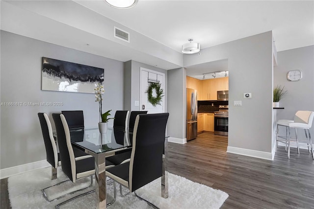 dining space featuring rail lighting and dark hardwood / wood-style flooring