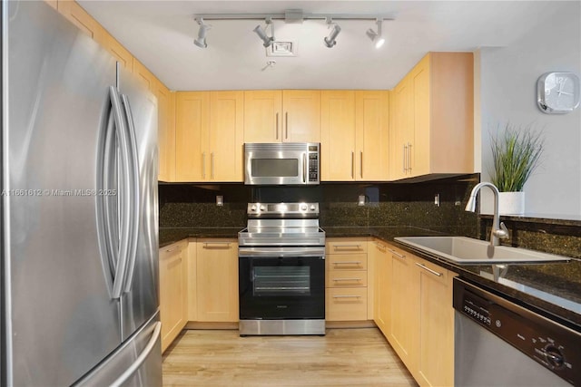 kitchen featuring sink, light brown cabinets, stainless steel appliances, and dark stone counters