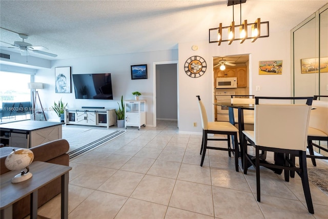 dining space with ceiling fan with notable chandelier, a textured ceiling, and light tile patterned floors