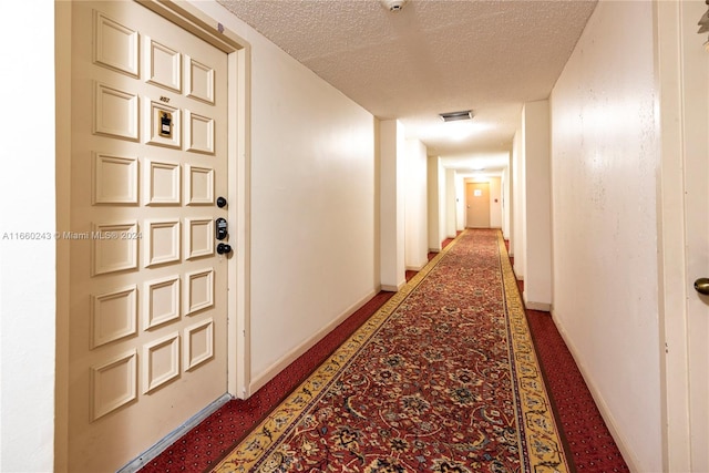 hall with a textured ceiling and carpet