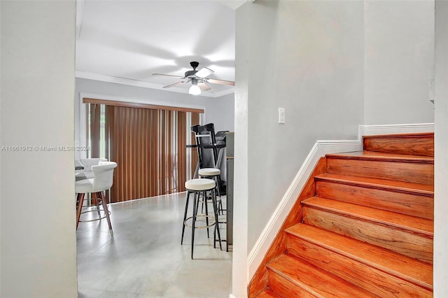 stairs with crown molding, ceiling fan, and concrete flooring