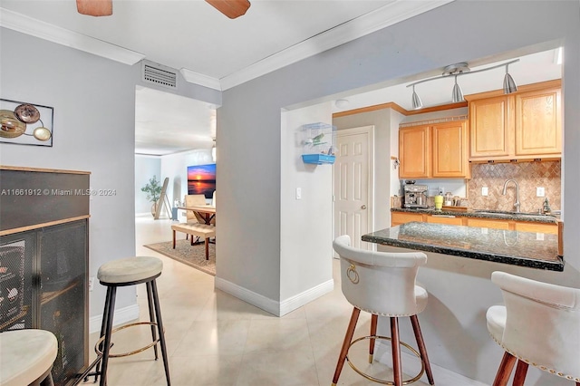 kitchen with a kitchen breakfast bar, ornamental molding, dark stone counters, and sink