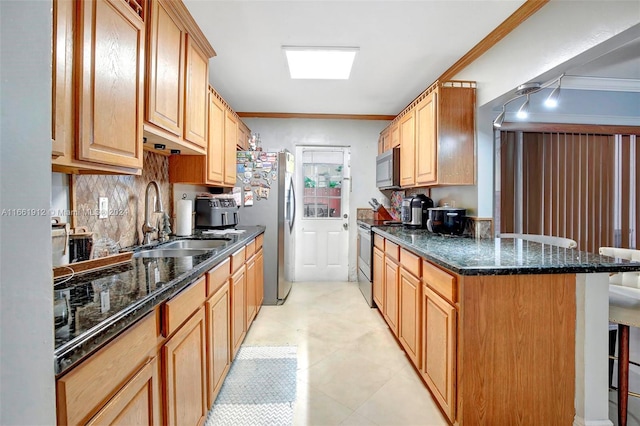 kitchen with a kitchen breakfast bar, ornamental molding, stainless steel appliances, sink, and dark stone countertops