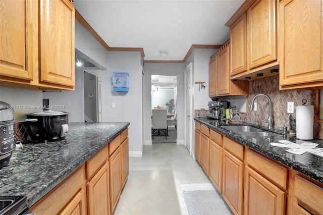 kitchen with backsplash, crown molding, dark stone countertops, and sink