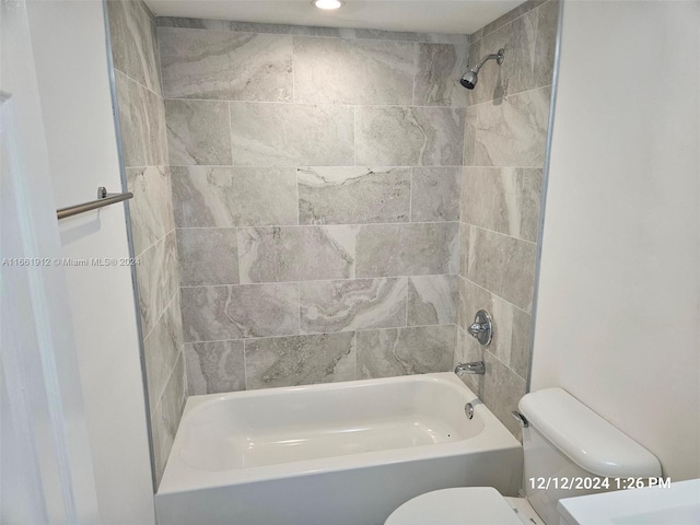 bathroom featuring toilet and tiled shower / bath