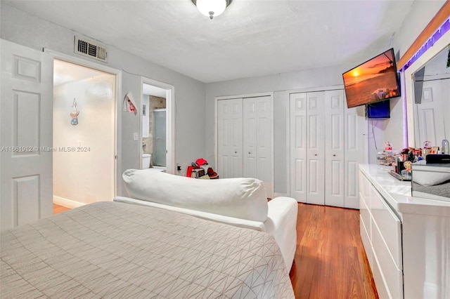 bedroom featuring connected bathroom, multiple closets, and light wood-type flooring