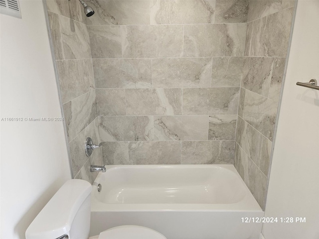 bathroom featuring toilet and tiled shower / bath