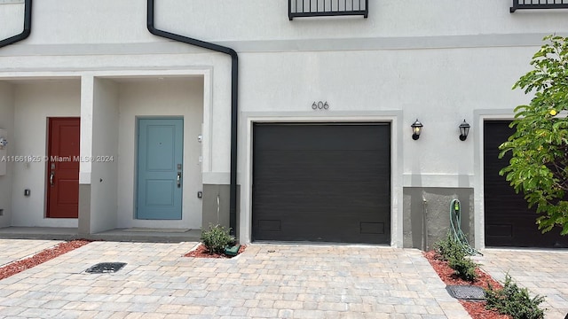 property entrance featuring decorative driveway and stucco siding