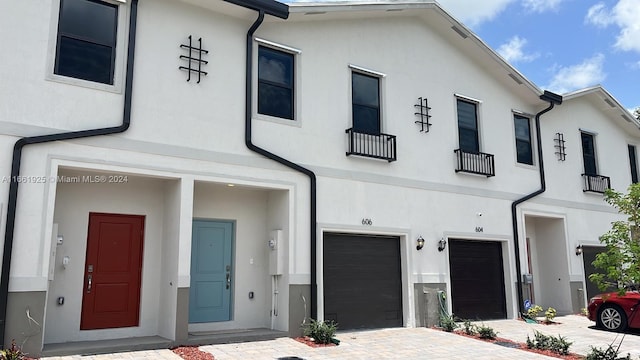 townhome / multi-family property with a garage, driveway, and stucco siding