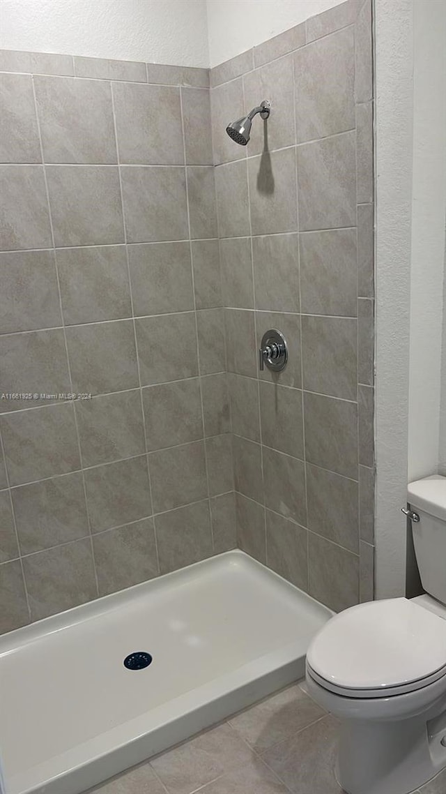 bathroom featuring a tile shower, toilet, and tile patterned floors