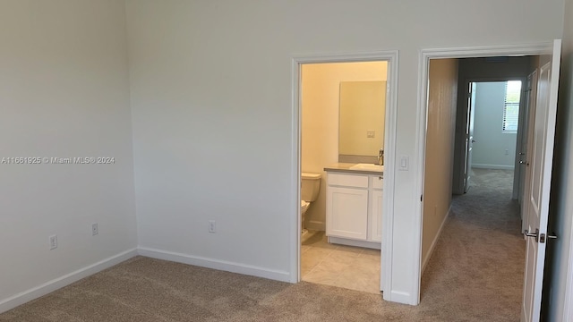 unfurnished bedroom featuring light carpet, connected bathroom, and sink