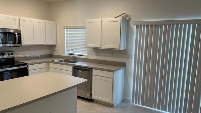 kitchen with appliances with stainless steel finishes, white cabinetry, and sink