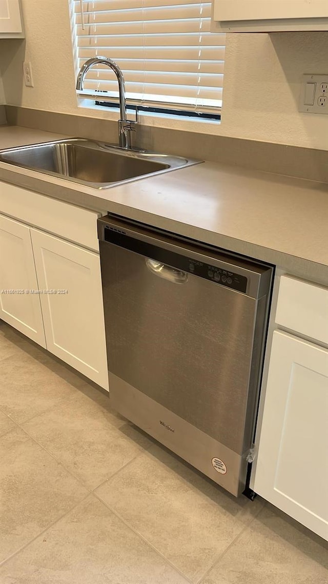 kitchen with light tile patterned floors, white cabinets, sink, and stainless steel dishwasher