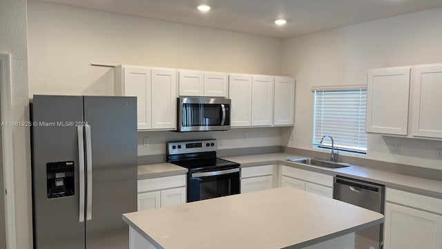 kitchen with a kitchen island, white cabinetry, a sink, and stainless steel appliances