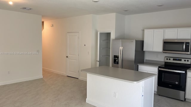 kitchen with visible vents, baseboards, a kitchen island, appliances with stainless steel finishes, and white cabinetry