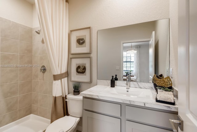 bathroom with toilet, vanity, a textured wall, and a shower stall