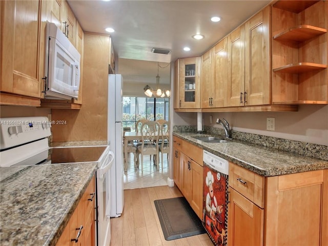 kitchen with light hardwood / wood-style floors, dark stone countertops, white appliances, an inviting chandelier, and sink