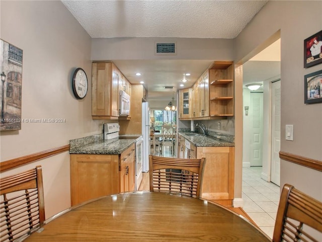 kitchen with a textured ceiling, sink, white appliances, and light tile patterned flooring