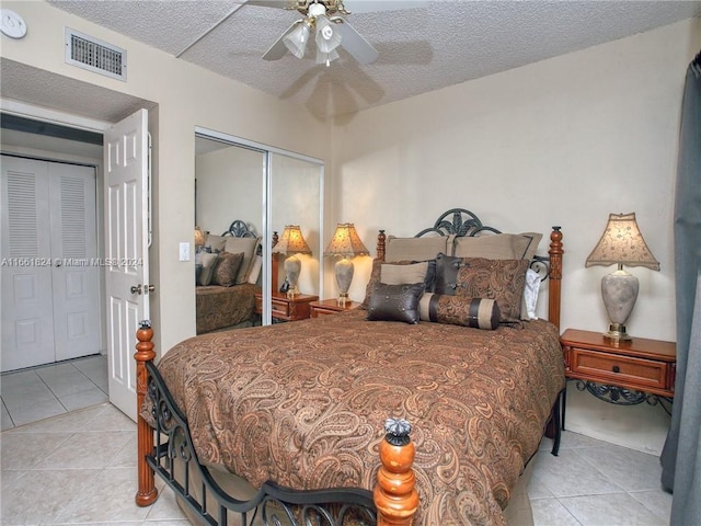 bedroom featuring ceiling fan, light tile patterned flooring, a closet, and a textured ceiling