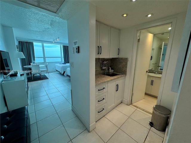 kitchen featuring white cabinetry, sink, light tile patterned flooring, and backsplash