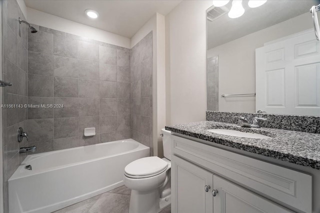 full bathroom featuring tile patterned flooring, tiled shower / bath combo, vanity, and toilet