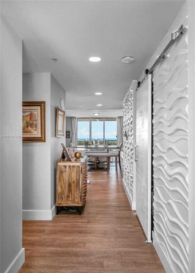 corridor with a barn door and hardwood / wood-style floors