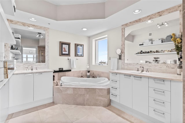 bathroom with tiled tub, vanity, and tile patterned flooring