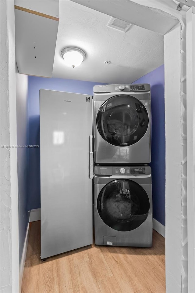 clothes washing area with stacked washing maching and dryer and hardwood / wood-style floors