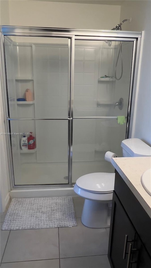 bathroom with vanity, tile patterned flooring, toilet, and an enclosed shower