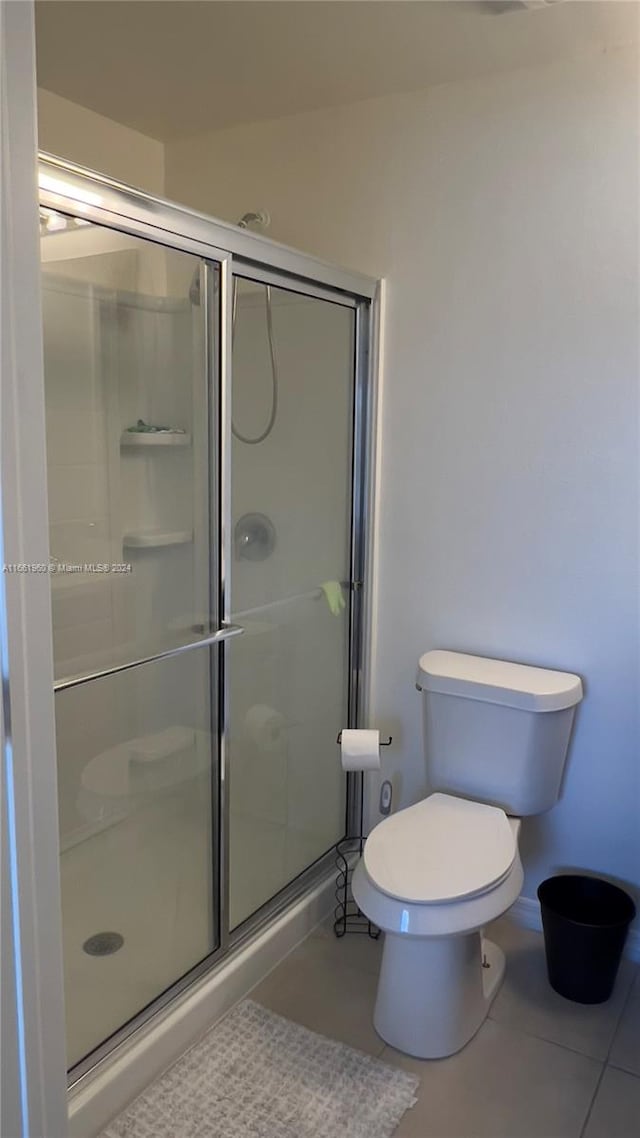 bathroom with toilet, walk in shower, and tile patterned floors