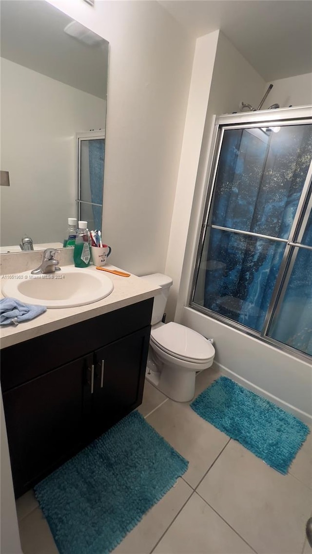 full bathroom featuring vanity, combined bath / shower with glass door, toilet, and tile patterned flooring