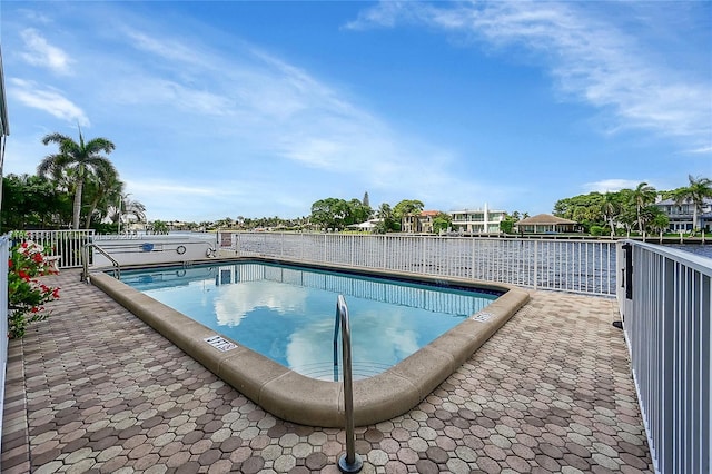 view of swimming pool with a patio and a water view