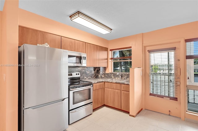 kitchen featuring light tile patterned floors, sink, tasteful backsplash, a textured ceiling, and appliances with stainless steel finishes