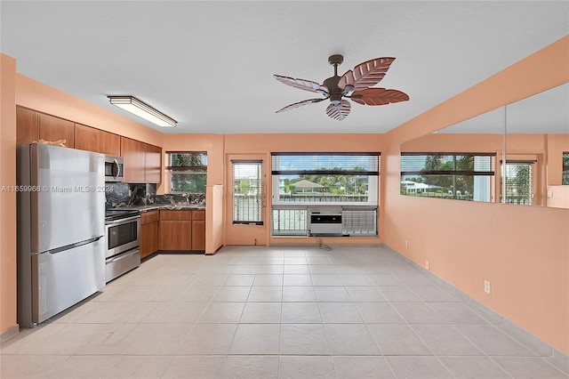 kitchen with light tile patterned flooring, tasteful backsplash, appliances with stainless steel finishes, decorative light fixtures, and ceiling fan