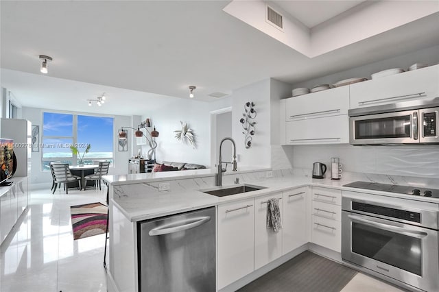 kitchen featuring sink, light stone countertops, white cabinetry, kitchen peninsula, and stainless steel appliances