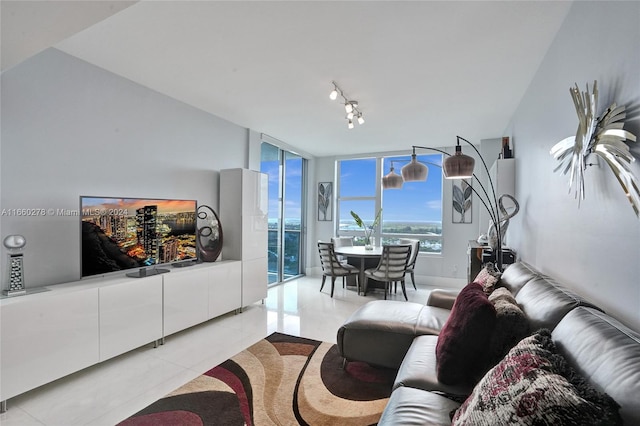 living room featuring light tile patterned floors, rail lighting, and a wall of windows