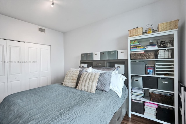 bedroom with dark hardwood / wood-style floors and a closet