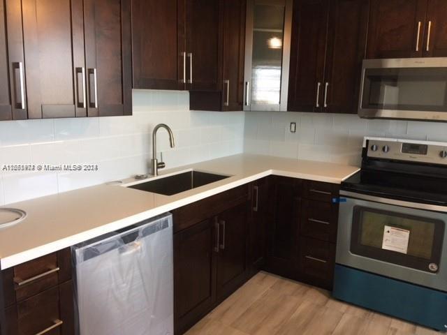 kitchen with appliances with stainless steel finishes, backsplash, dark brown cabinets, light hardwood / wood-style flooring, and sink