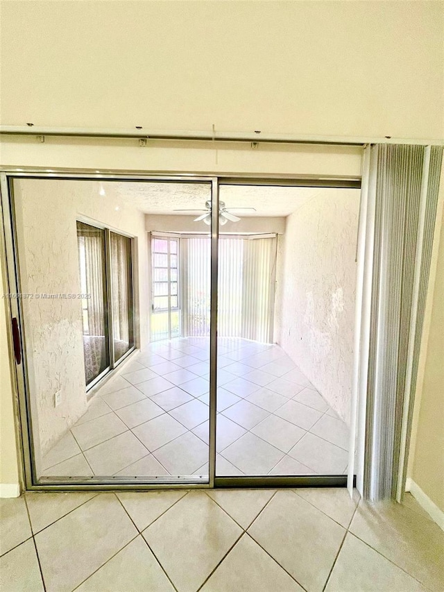 doorway with tile patterned floors and ceiling fan