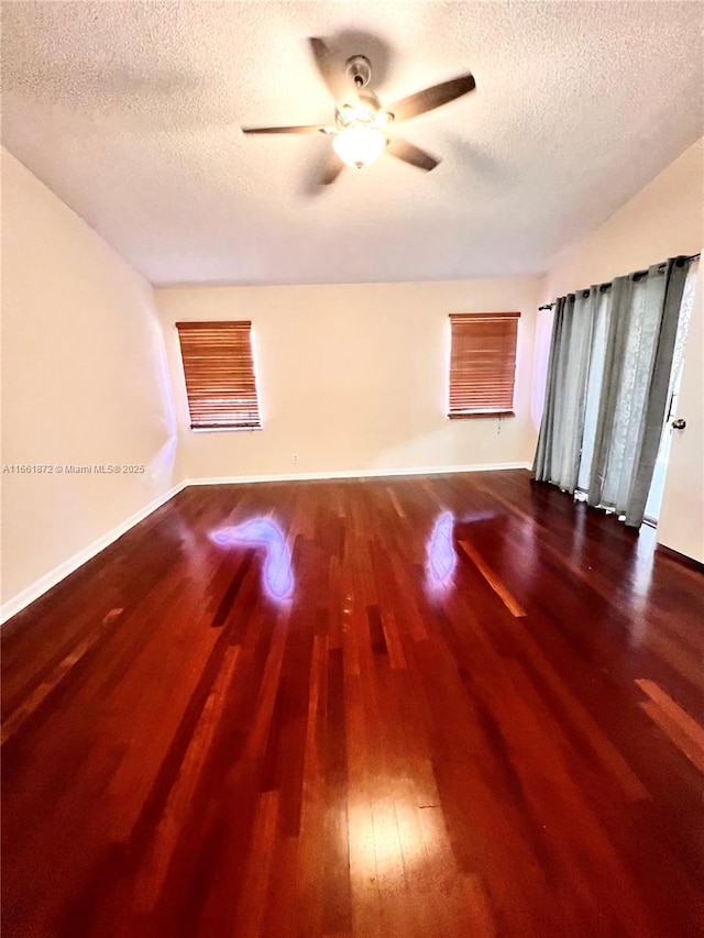 unfurnished room featuring a textured ceiling, ceiling fan, and dark wood-type flooring