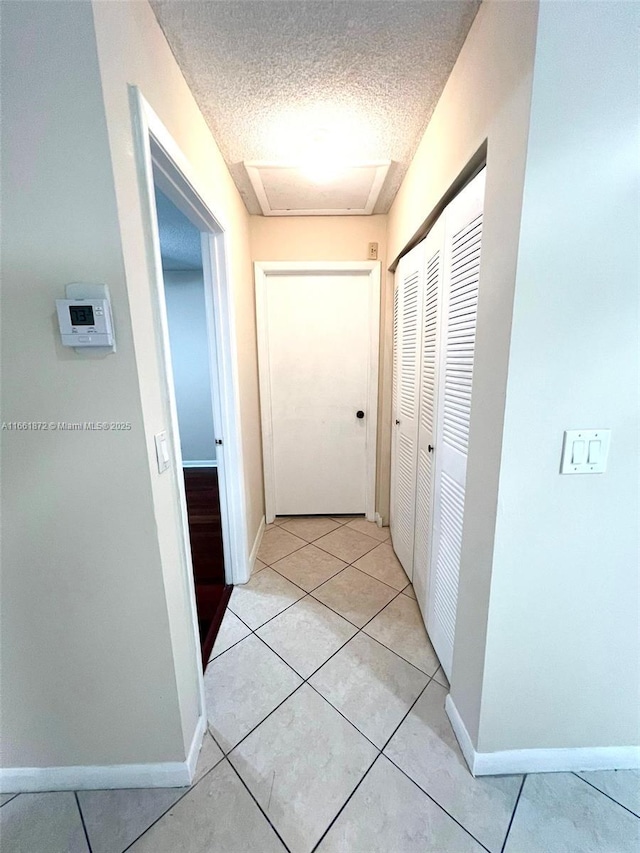 corridor with light tile patterned floors and a textured ceiling