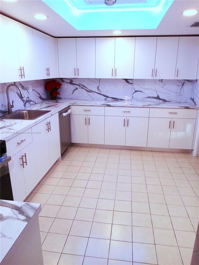 kitchen with dishwasher, white cabinetry, sink, a raised ceiling, and light stone countertops