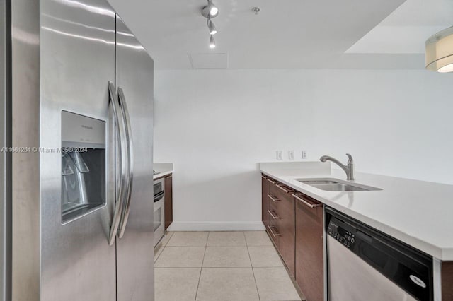 kitchen with rail lighting, light tile patterned flooring, stainless steel appliances, dark brown cabinets, and sink