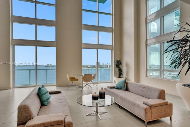 tiled living room featuring a water view and a towering ceiling