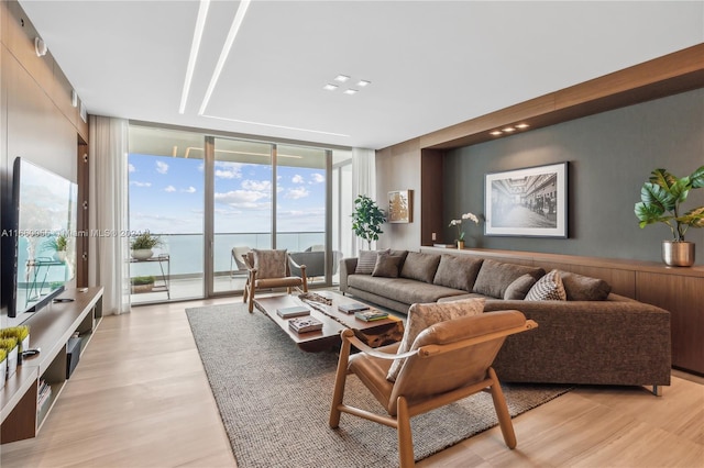 living room featuring light hardwood / wood-style flooring, a water view, and a wall of windows